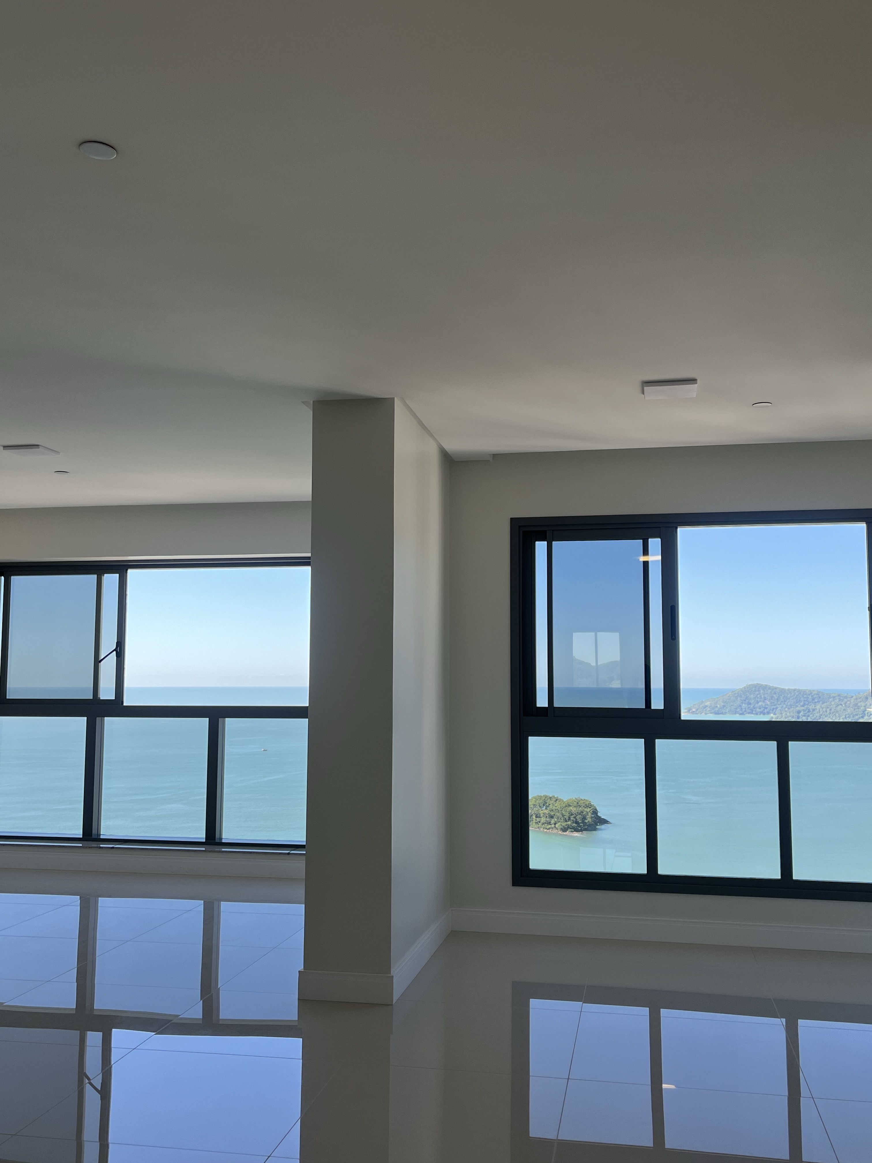 Living do apartamento com pé-direito amplo e vista para o mar